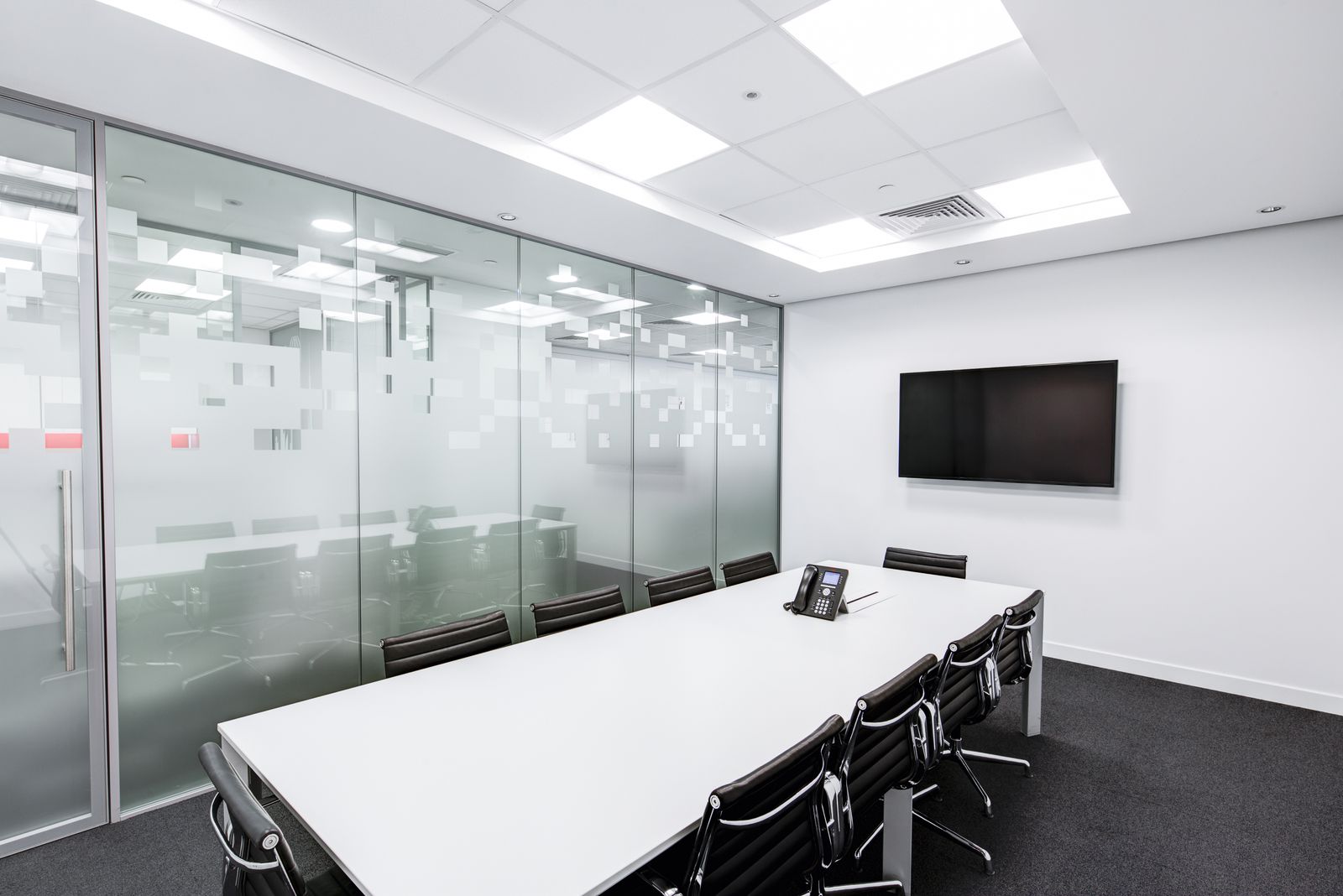 Sleek glass-walled conference meeting room with long table